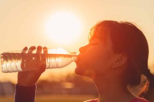 Female drinking a bottle of water during a summer heat emergency
