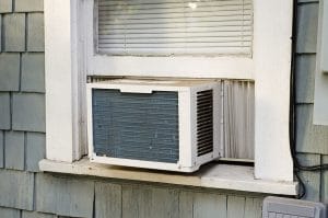 Eine Klimaanlage ragt aus einem Fenster.