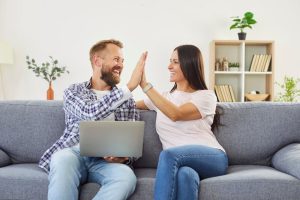 Happy couple at home, man and woman high five to celebrate getting a rebate on heat pump upgrade