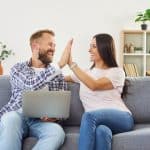 Happy couple at home, man and woman high five to celebrate getting a rebate on heat pump upgrade