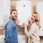 smiling boyfriend and girlfriend deciding between hot water heater or boiler in home appliance store