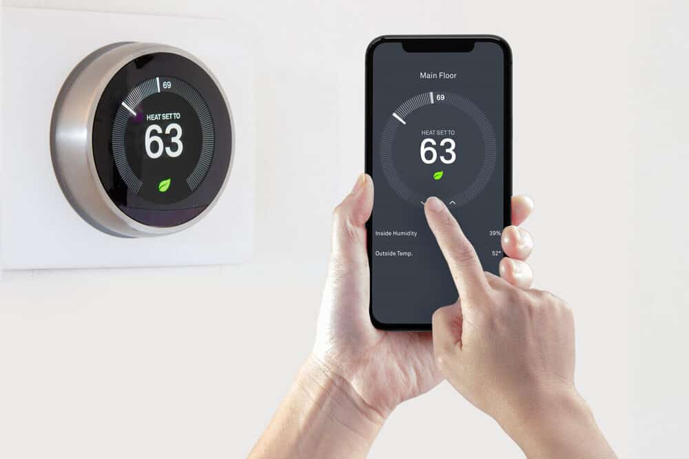 A person using a smart phone application saving energy with a smart thermostat