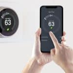 A person using a smart phone application saving energy with a smart thermostat