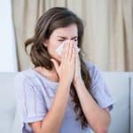woman with allergies blowing her nose