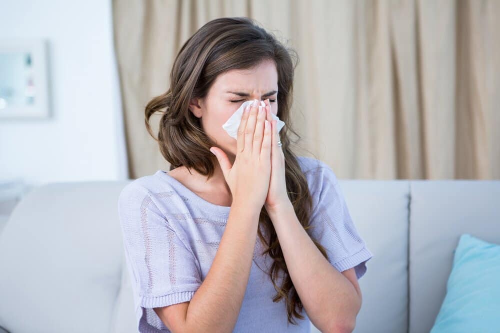 woman with allergies blowing her nose