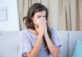 woman with allergies blowing her nose