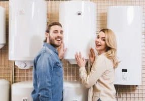 smiling boyfriend and girlfriend deciding between hot water heater or boiler in home appliance store