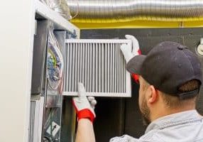 HVAC service technician changing dirty air filter in the central ventilation system