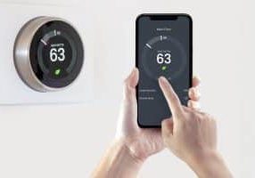 A person using a smart phone application saving energy with a smart thermostat