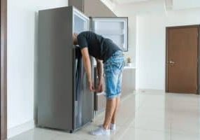 On a hot day, the guy cools with his head in the refrigerator. Broken air conditioner.